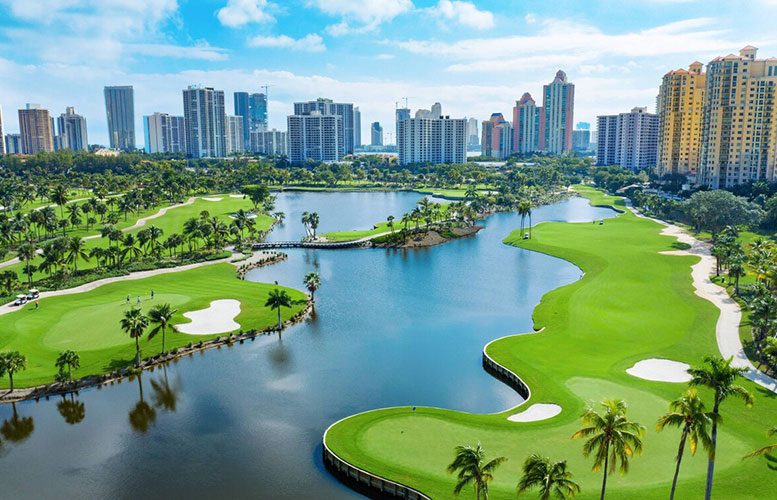 Aerial view of Country Club Drive — golf course lakes, palm-lined fairways, and the Aventura skyline