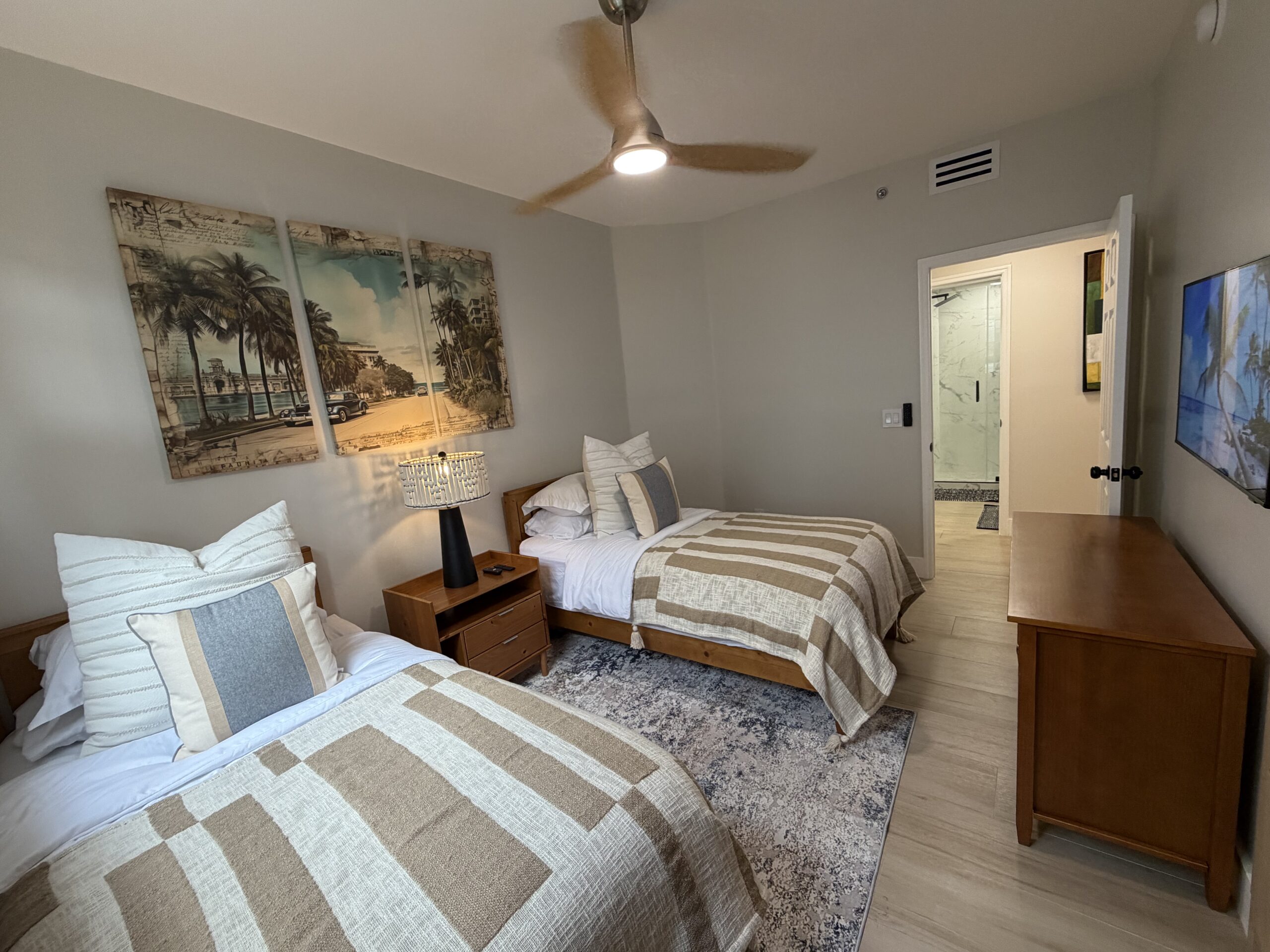 Second bedroom with bedding, side table, and decor in the Aventura two-bedroom rental
