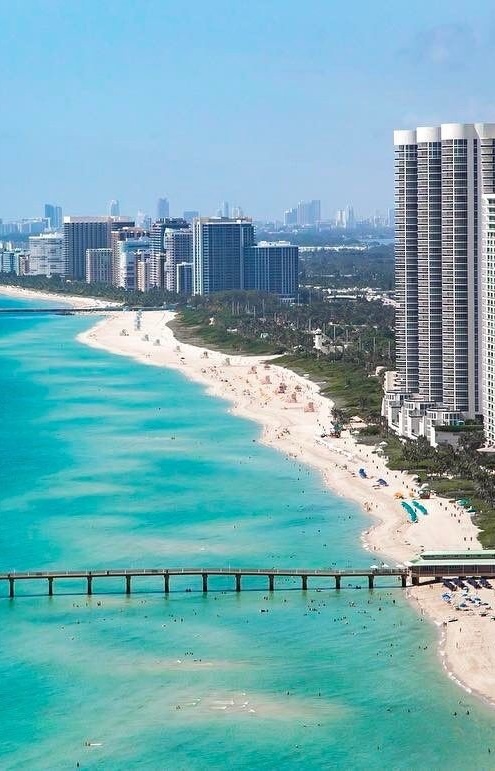 Aerial view of Sunny Isles Beach with turquoise water, white sand, the pier, and the high-rise skyline