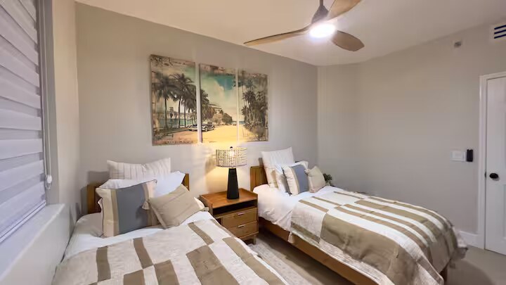 Second bedroom with two twin beds and a triptych beach artwork