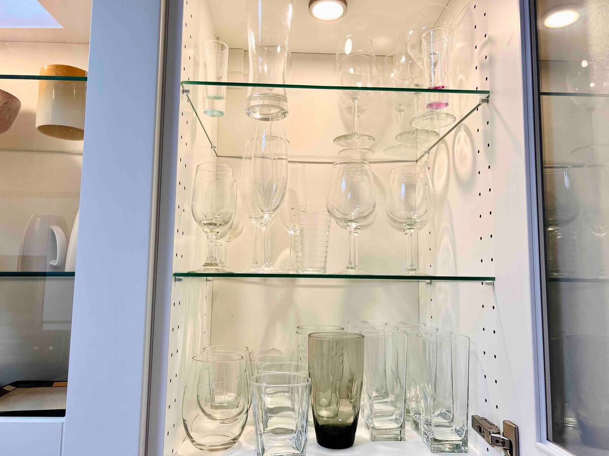 Glass-front cabinet stocked with wine glasses, champagne flutes, and stemware in the one-bedroom kitchen