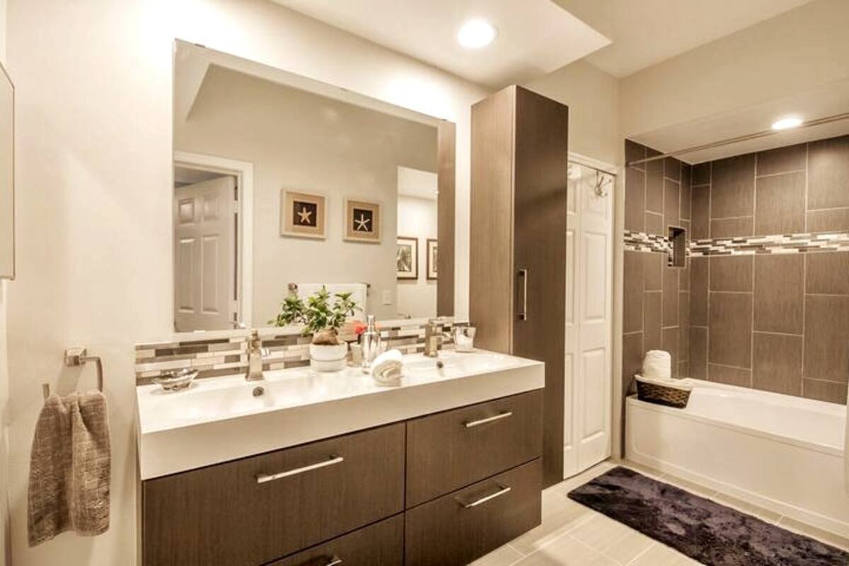 Bathroom with a double-sink vanity, walk-in tiled shower, and soaking tub in the Aventura one-bedroom apartment