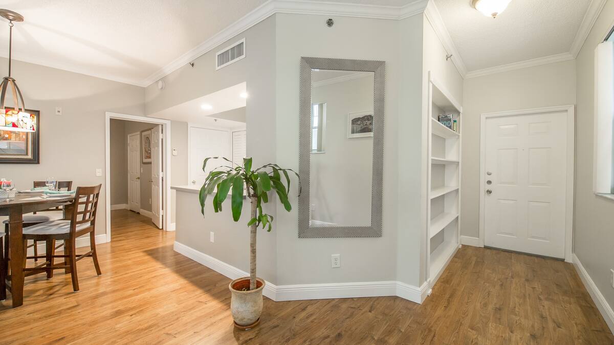 Foyer with a full-length mirror, built-in shelving, and hardwood floors at the apartment entrance