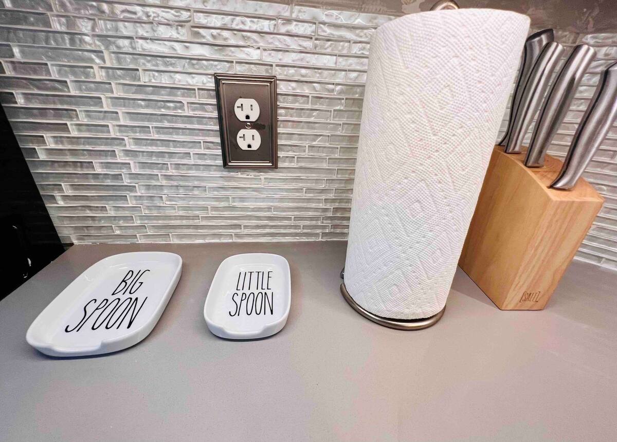 Kitchen counter detail with a knife block, spoon trays, and subway-tile backsplash
