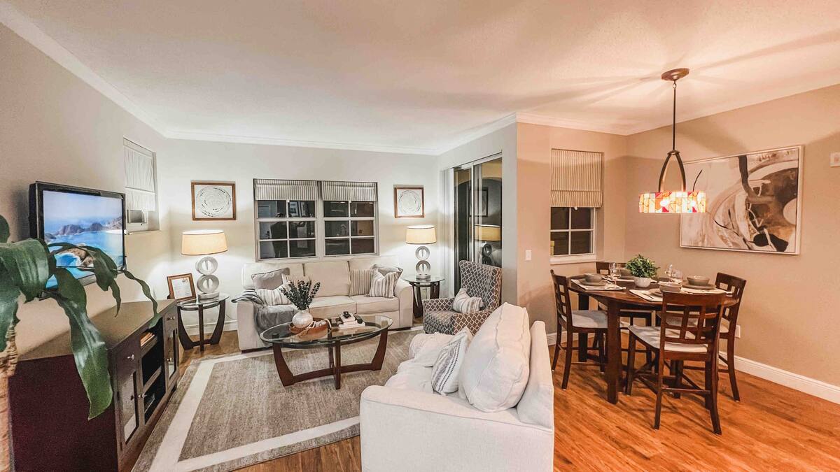 Open-plan living and dining area with hardwood floors and natural light in the one-bedroom apartment at Village By The Bay