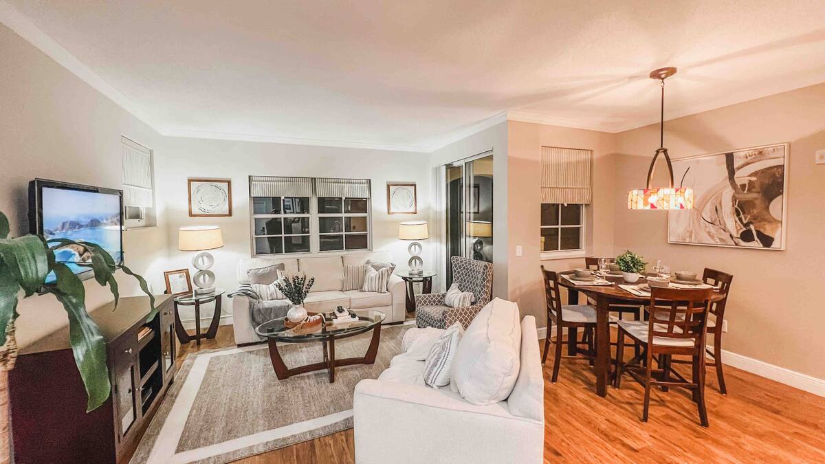 Open-plan living and dining area in evening light with the chandelier on at the Aventura one-bedroom apartment