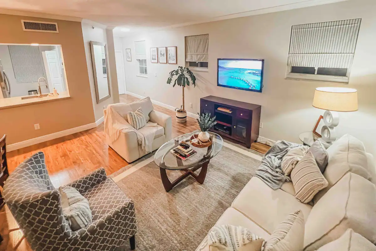 Cozy living room with TV, sofa, woven accent chair, and beachy decor in the one-bedroom rental