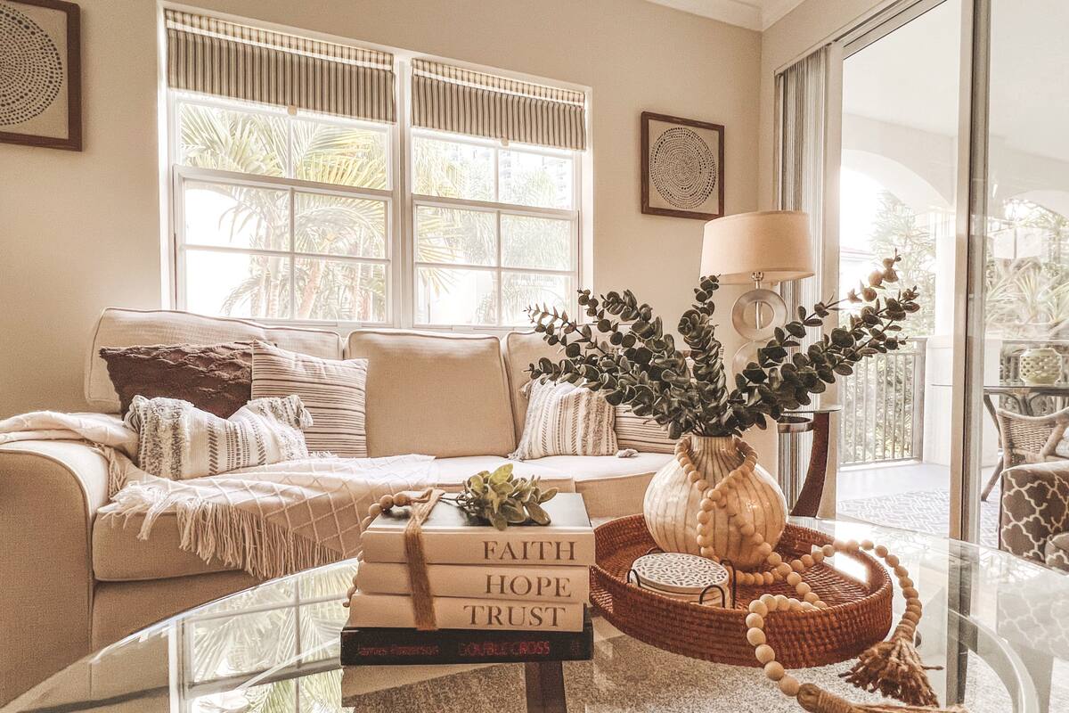 Cozy reading corner with sofa, coffee-table books, and a sunny window facing the palms