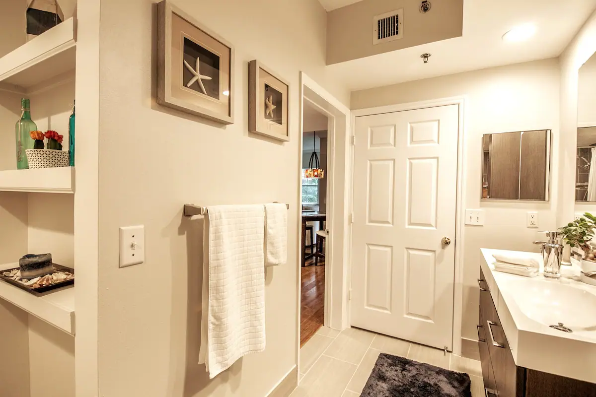 View from the bedroom toward the bathroom and entrance, with a towel rack and vanity